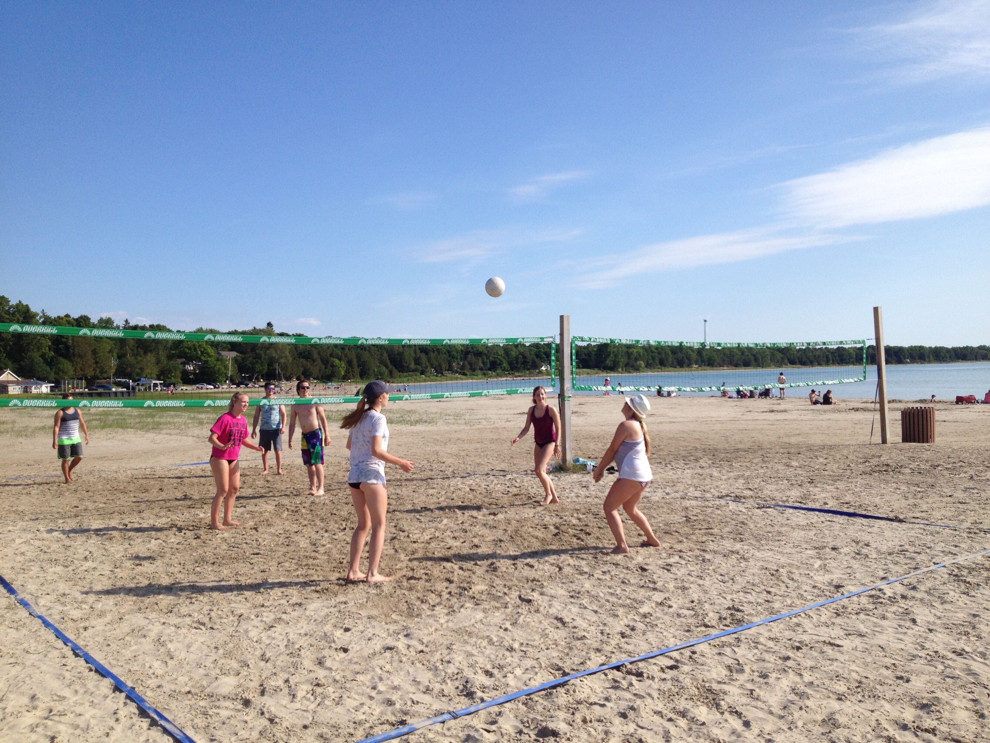 A beach volleyball game with players in various outfits.