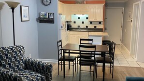 Un espacio habitable compacto con comedor, kitchenette y un sofá estampado.