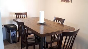 A dining table with four chairs, a trash can, and a white candle on the table.
