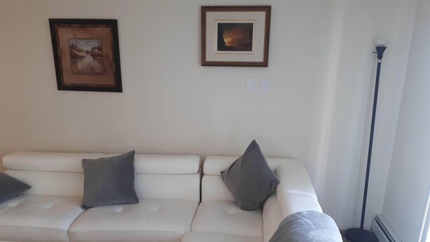 A living room with a white sofa, two grey cushions, and a floor lamp.