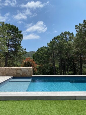 A swimming pool with a stone wall and a grassy area. - CASA ALTI - ARCHITECT'S HOUSE - PORTO VECCHIO (Lecci)