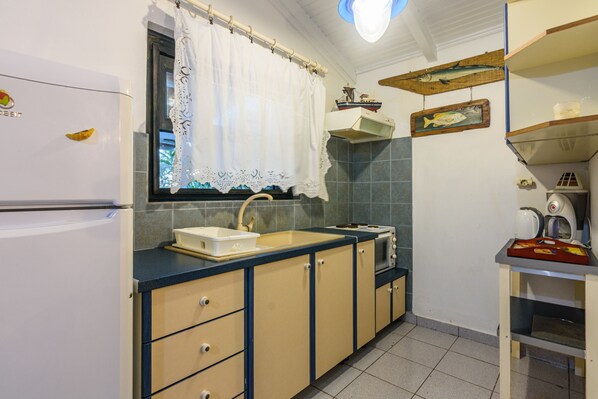 A compact kitchen with a sink, stove, and cabinets.
