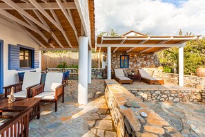 A covered outdoor seating area with stone walls and wooden furniture.