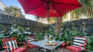 A patio with a table, chairs, and a red umbrella. - Casa Bella - Suite A | Downtown Beauty from 1800s (Charleston)