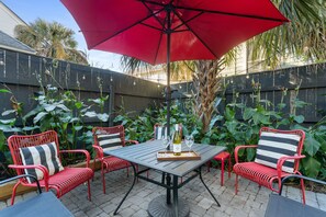 Une terrasse extérieure avec un parasol rouge, une table et des chaises rouges dotées de coussins à rayures.