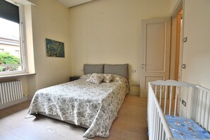 A bedroom with a bed, a crib, a window, and a door.