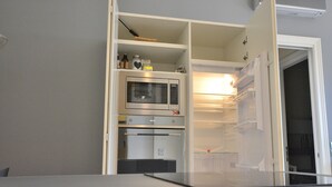 A compact kitchen with a built-in microwave, oven, and refrigerator. - Residenza Vecchia Veronetta (Verona)