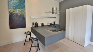 A modern kitchen with a central island, a hanging light fixture, and a large abstract painting on the wall. - Residenza Vecchia Veronetta (Verona)