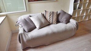 A modern living room with a sofa, pillows, a painting, and a bookshelf. - Residenza Vecchia Veronetta (Verona)