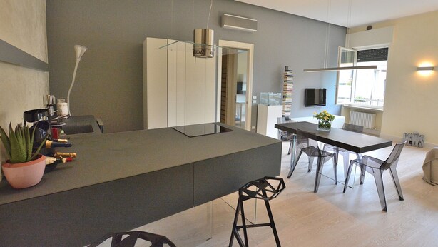A modern kitchen with a central island, bar stools, and a dining area. - Residenza Vecchia Veronetta (Verona)