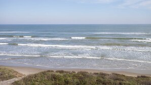Una spiaggia con onde, cielo sereno e litorale sabbioso.