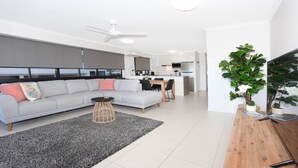 A modern living room with a grey sofa, a small round table, and a ceiling fan. - Unit 1 'Phoenix' /1736 David Low Way, Coolum Beach (Coolum Beach)