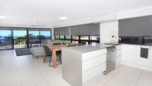 A modern kitchen with a large island, white cabinetry, and a view of the ocean. - Unit 1 'Phoenix' /1736 David Low Way, Coolum Beach (Coolum Beach)