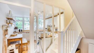 A kitchen with white cabinetry, a wooden table, and a staircase leading to another level.