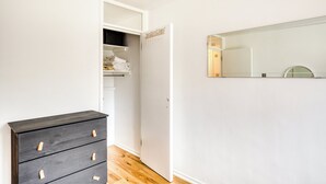 Une pièce avec une commode en bois, un placard contenant des serviettes pliées et un miroir au mur.