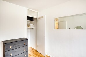 Ein Zimmer mit einem Holzkoffer, einem Schrank mit gefalteten Handtüchern und einem Spiegel an der Wand.