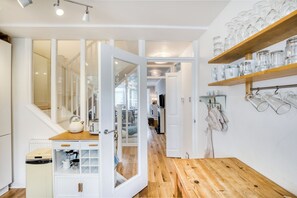 A kitchen with wooden flooring, white cabinetry, and a glass door leading to a dining area.
