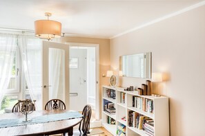 Un coin repas avec une table et des chaises, une bibliothèque remplie de livres, une horloge et un miroir accroché au mur.