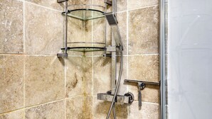 A shower with a handheld showerhead and a fixed wall-mounted faucet. - Spacious and Stylish 4BDR Home w Garden in Brixton (London)