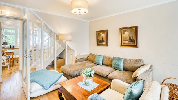 A living room with a sofa, coffee table, and a staircase leading to another room. There are two framed pictures on the wall. - Spacious and Stylish 4BDR Home w Garden in Brixton (London)