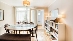 A dining area with a table, chairs, a candelabra, and a bookshelf with books and decorative items. - Spacious and Stylish 4BDR Home w Garden in Brixton (London)