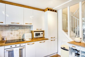 A modern kitchen with white cabinetry, wooden countertops, and a built-in microwave.
