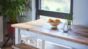 Ein Holztisch mit einer Schale Orangen und einer Topfpflanze.