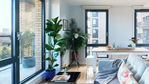 Ein modernes Wohnzimmer mit großem Fenster, einer Couch, einem Couchtisch und verschiedenen Pflanzen.