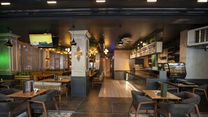 Ein Restaurantinneres mit mehreren Sitzbereichen, einer Bar und einem Fernsehbildschirm.