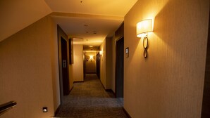 Ein Hotelgang mit Teppichböden, einer Handläufe und einer Wandleuchte.