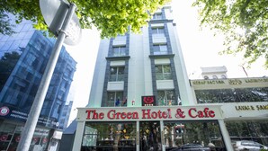 Das Green Hotel & Cafe mit einer modernen Fassade, großen Fenstern und einer Schautafel.