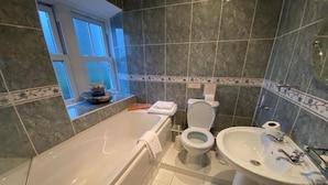 A modern bathroom with a bathtub, toilet, and sink. - OYO Lamphey Hall Hotel (Pembroke)