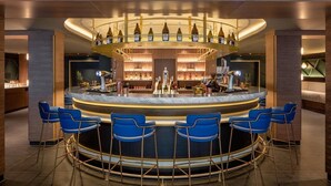 A bar area with a curved counter, blue bar stools, and a variety of bottles and glasses on shelves. - Yotel Edinburgh (Edinburgh)