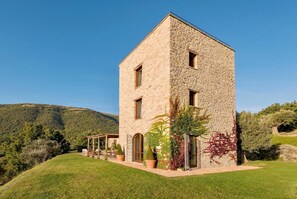 A stone tower house with a covered patio and potted plants.