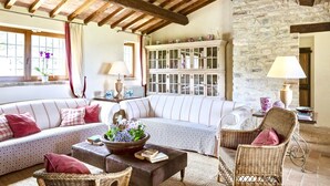 A cozy living room with a stone wall, wooden beams, a large sofa, and wicker furniture. - BELLAVISTA - Three Bedroom Villa, Sleeps 8 (Perugia)