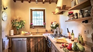 A kitchen with wooden cabinets, a built-in dishwasher, a window with a view, and various kitchen items like a bread loaf, apples, and bottles. - BELLAVISTA - Three Bedroom Villa, Sleeps 8 (Perugia)