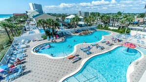 A large, multi-lane swimming pool with lounge chairs and umbrellas, surrounded by palm trees and buildings. - # 505~BeachFront 5th Floor Movie Theater~ Pools ~ Game Rm~ Majestic Beach Resort (Panama City Beach)