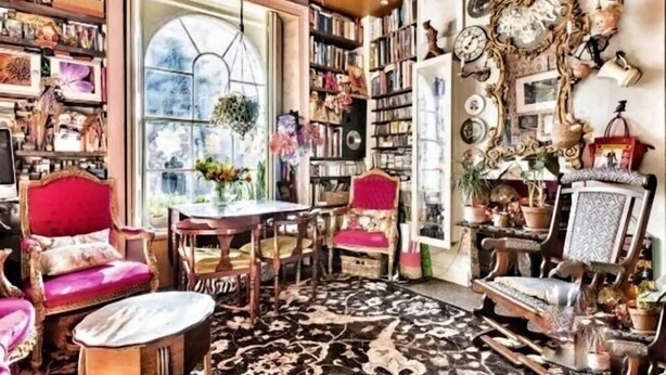 A cozy room with a large window, a bookshelf filled with books, a red chair, and a patterned rug. - Boutique bijoux garden flat in vibrant Oval (London)