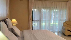 Hotellihuone, jossa on sänky, tyynyjä, lamppu ja tuoli.