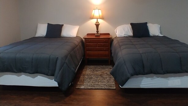 A bedroom with two beds, a nightstand with a lamp, and a rug. - Apartment 2- 2760 Carters Ferry Road Milam Texas.        Free Ice !!!  (Milam)