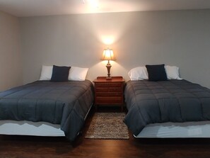 Une chambre avec deux lits, une table de chevet avec une lampe et un tapis.
