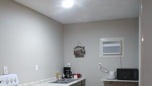 A small kitchen with a white stove, a coffee maker, a microwave, and a wall-mounted air conditioner. - Apartment 2- 2760 Carters Ferry Road Milam Texas.        Free Ice !!!  (Milam)
