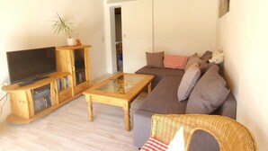 A living room with a television, wooden furniture, a sofa, and a wicker chair.