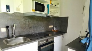 A compact kitchen with a built-in microwave, oven, and sink. - Vacation apartment "Eselstube"! Vacation on a farm in the Eifel (Nettersheim)