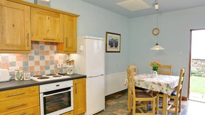 Une cuisine avec des meubles de rangement en bois, un réfrigérateur blanc, une cuisinière et une table à manger avec des chaises.