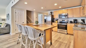 Una cocina moderna con armarios de madera, electrodomésticos de acero inoxidable y una isla central con taburetes de bar.