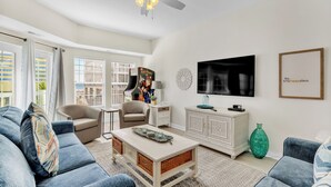 Una sala de estar con sofá, sillón, mesa de centro, televisor y objetos decorativos.