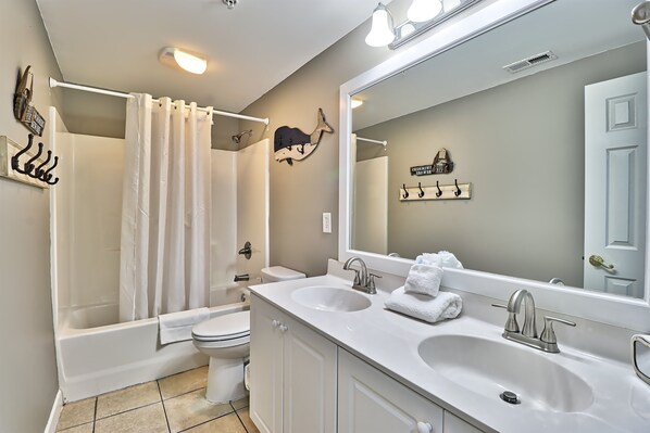 A modern bathroom with a bathtub, toilet, and a double sink vanity.