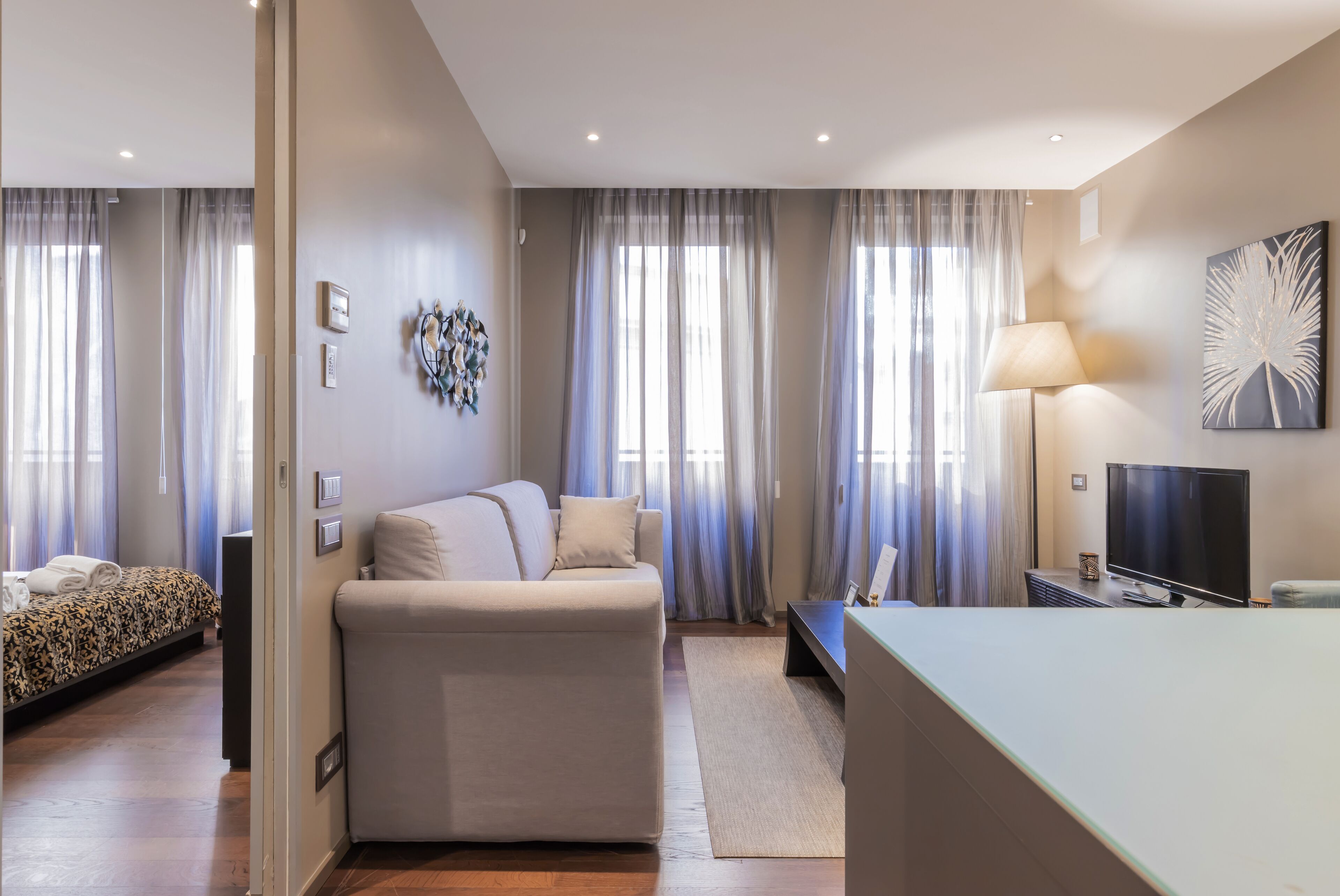 Une chambre d’hôtel moderne, équipée d’un canapé, d’une télévision et d’un lit avec une couvre-lit à motifs.