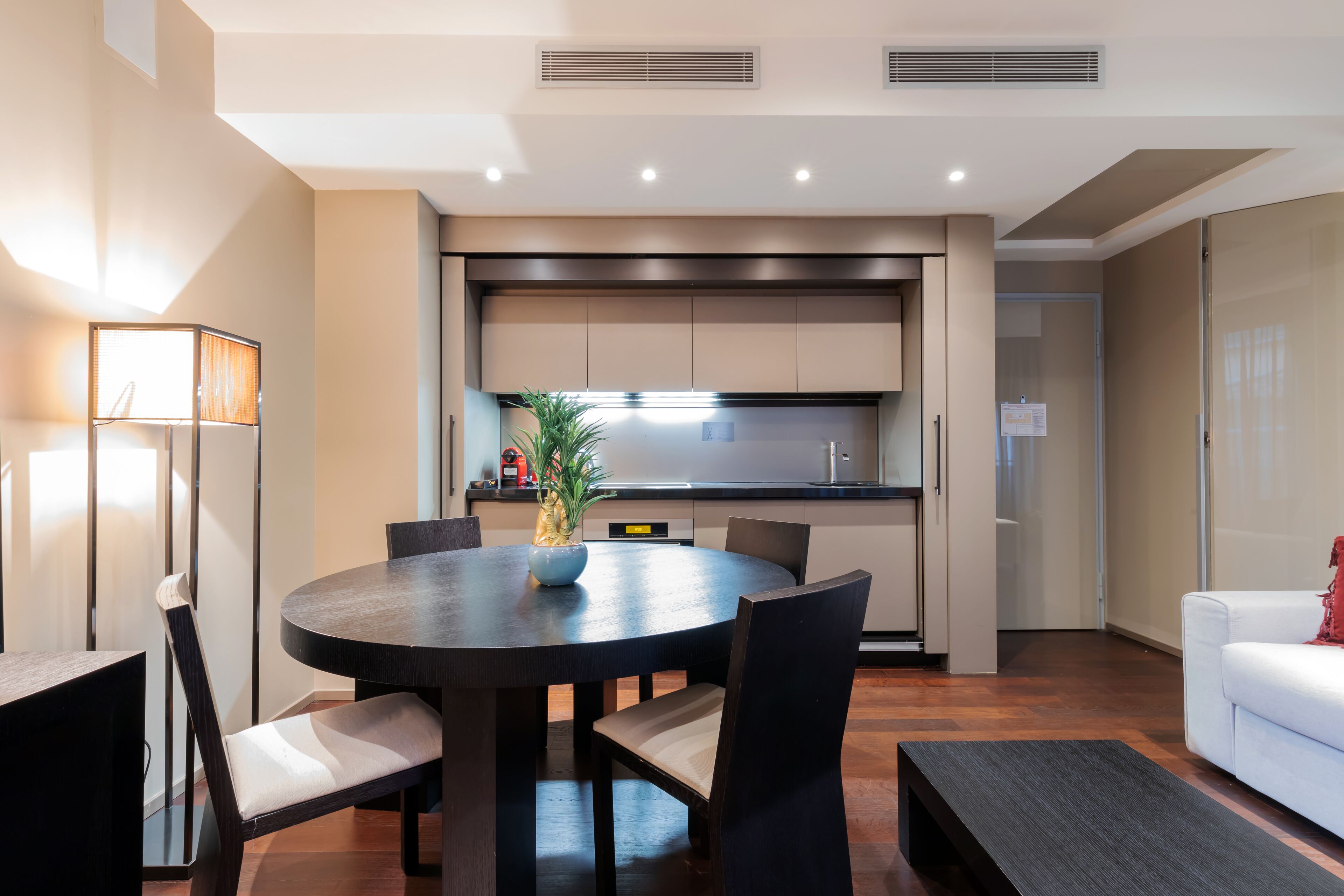 A modern kitchen with a central island, a dining table with chairs, and a white sofa.